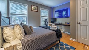 A bedroom with a bed, a desk, a chair, a TV, and a window. - 3 Bedroom Homestead Getaway - Walkable Carrboro, Minutes to UNC (Carrboro)