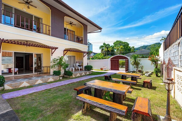 A two-story building with a covered patio, outdoor seating area, and a pool. - Chernin Apartment Suites, Rawai (Rawai)