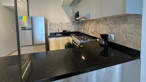 A modern kitchen with a black countertop, stainless steel appliances, and a patterned backsplash. - Federalta Sky Life Apartment in Calzada del Federalismo (Zapopan)