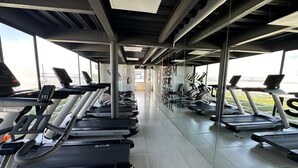 A gym with multiple treadmills aligned in rows, a mirrored wall, and a view of the outdoors. - Federalta Sky Life Apartment in Calzada del Federalismo (Zapopan)