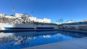 A swimming pool with clear blue water, surrounded by white walls and a tiled deck. - Federalta Sky Life Apartment in Calzada del Federalismo (Zapopan)