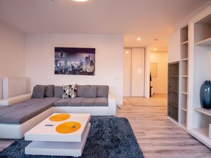 A modern living room with a sectional sofa, a white coffee table with yellow accents, and a cityscape painting on the wall. - Luxuriöse Präsidentensuite by Interhome (Bucuresti)