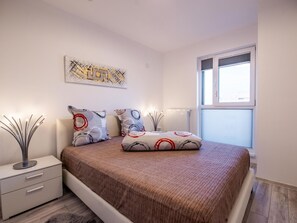 A bedroom with a bed, a bedside table, a radiator, and a window. - Luxuriöse Präsidentensuite by Interhome (Bucuresti)