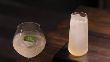 Three glasses of beverages on a wooden table with a dark background.
