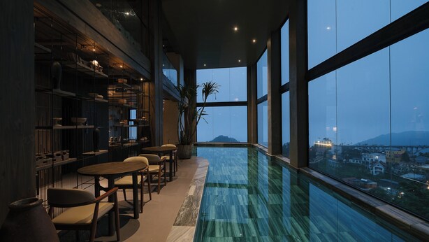 Una piscina interior moderna con vistas a un paisaje urbano al anochecer.