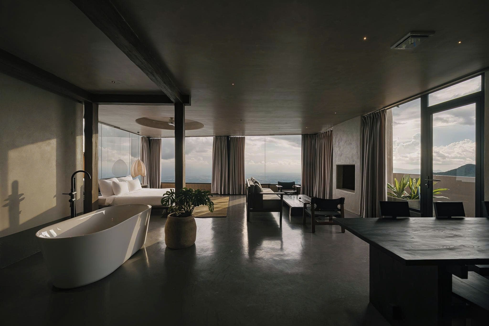 A spacious room with a large bathtub, a seating area with a view, and a dining table.