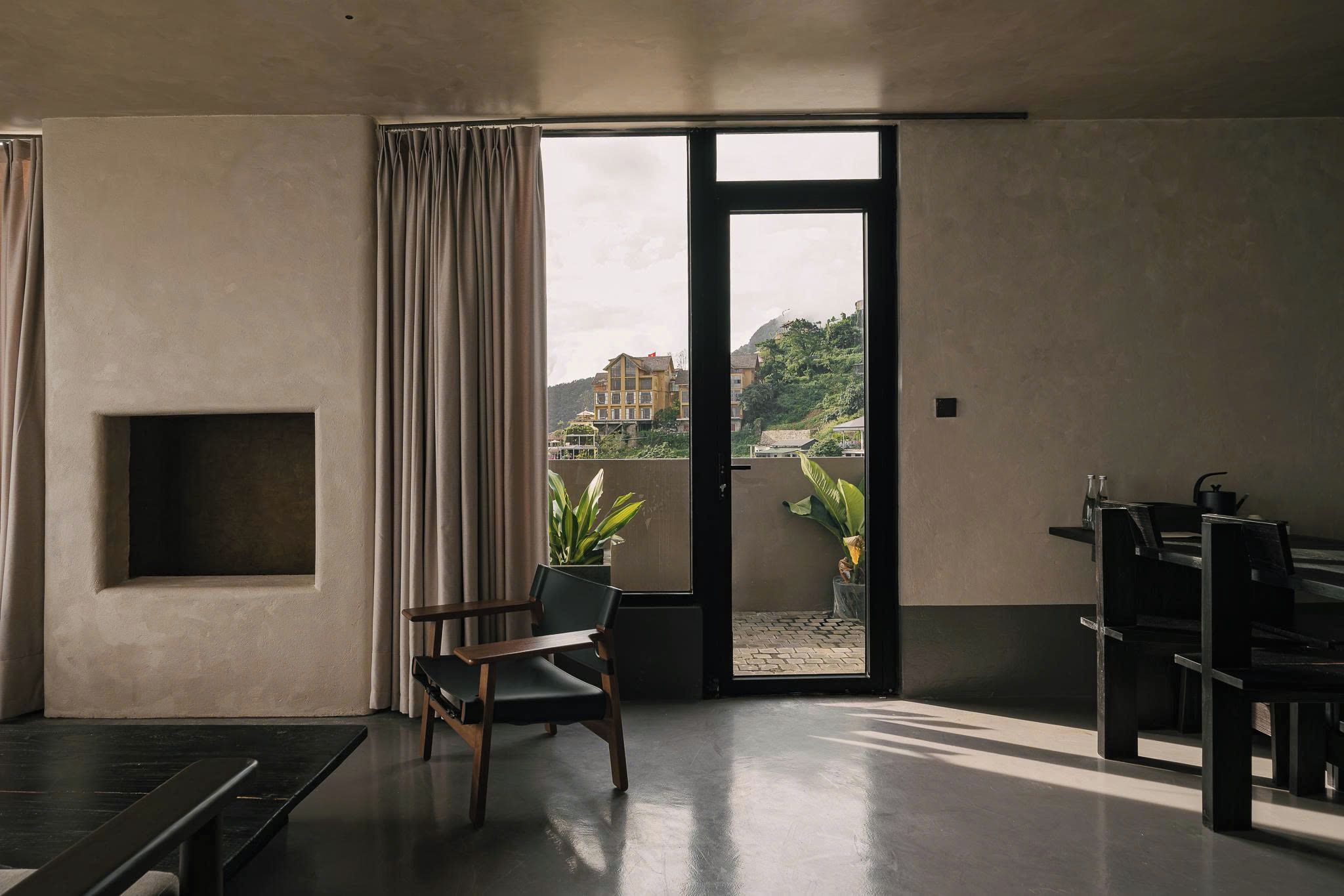 A modern interior with a sliding glass door leading to a balcony, a seating area with a chair, and a small table.