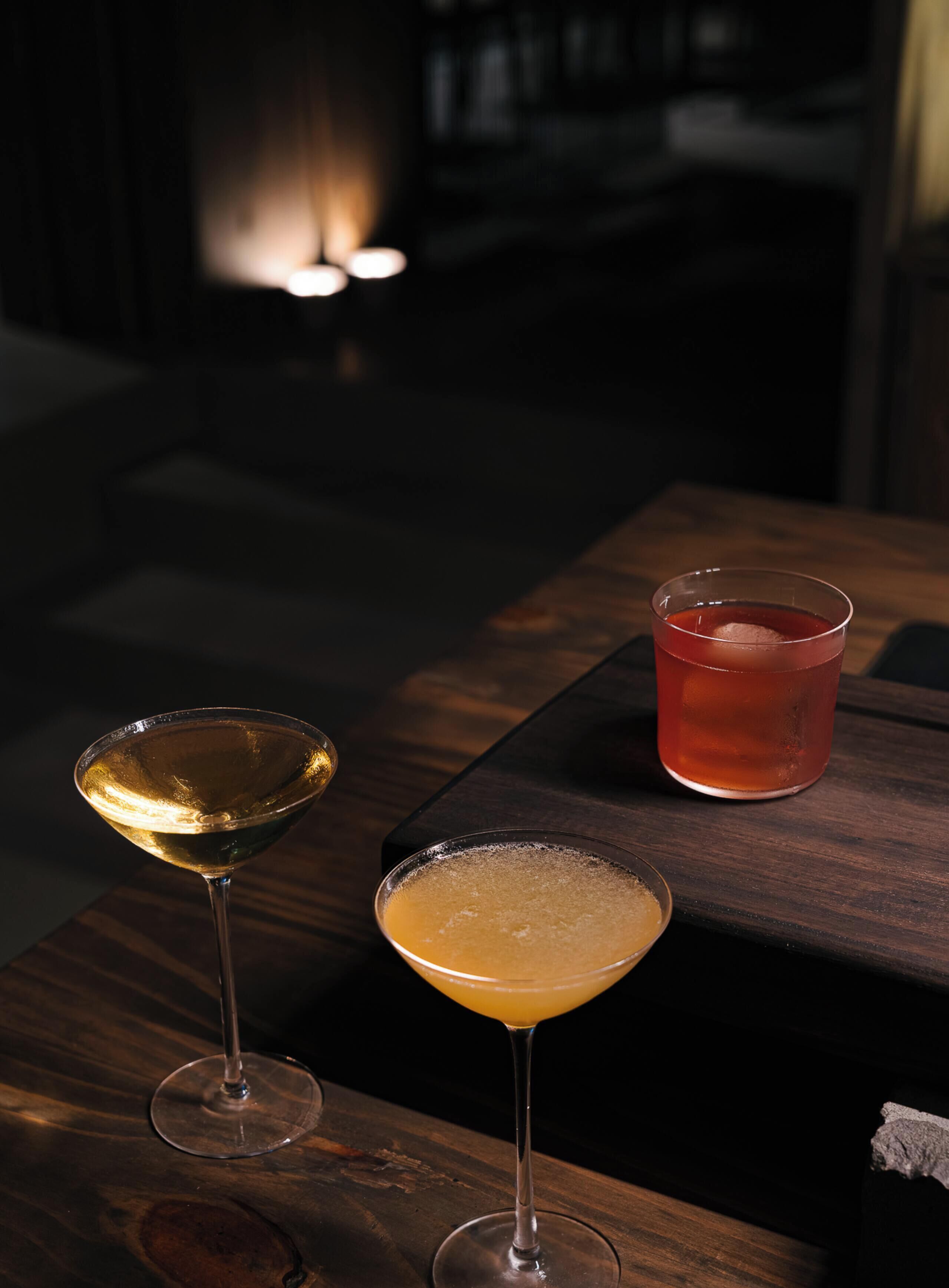 Two drinks on a wooden table with a dimly lit background.