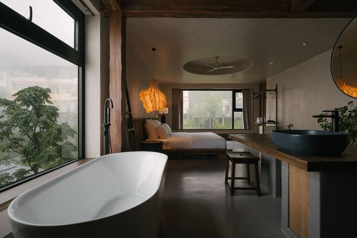 Un baño moderno con una bañera independiente, un tocador de madera y un espejo grande.