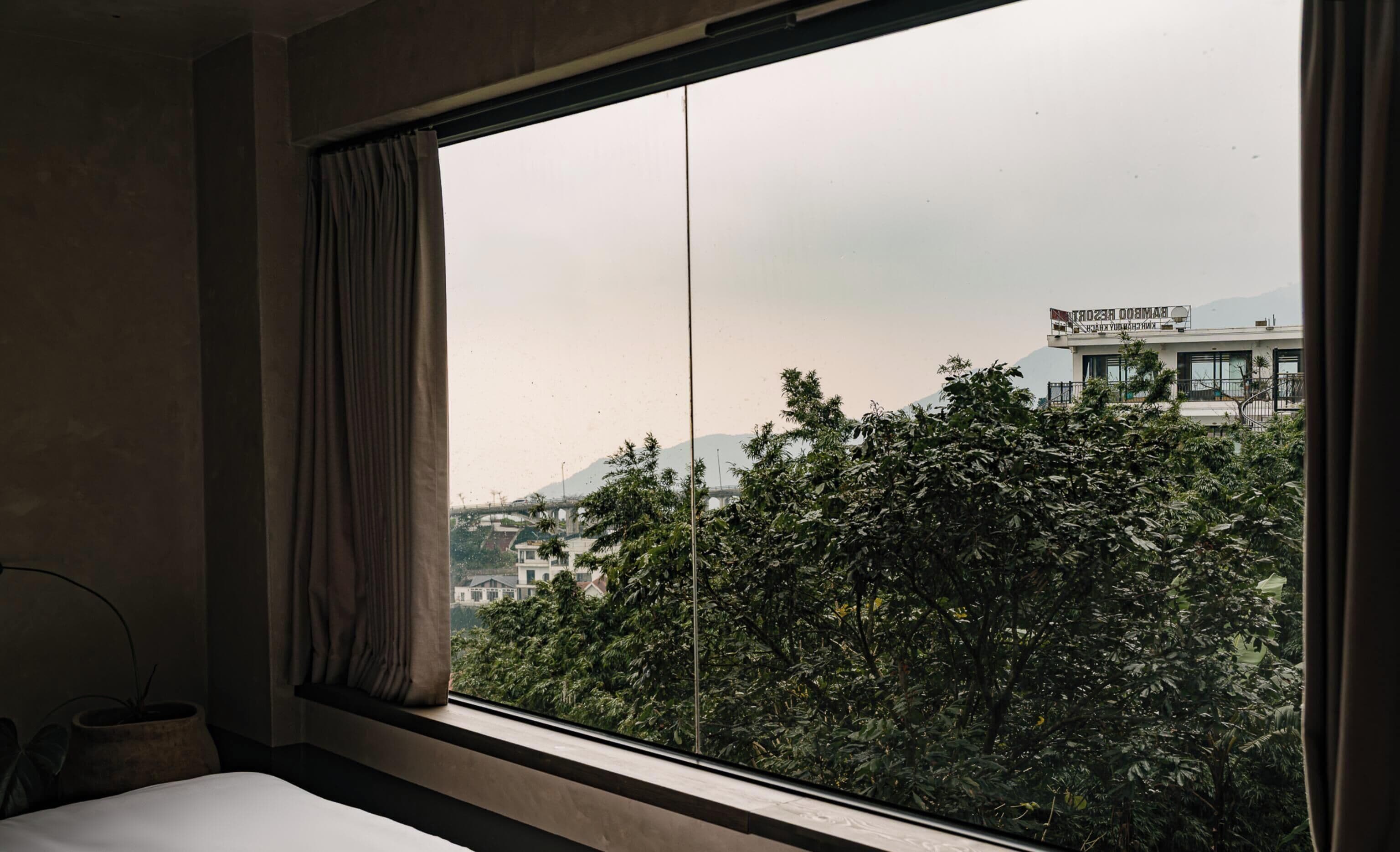 Una habitación con un ventanal grande, una cama y una cortina.