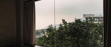 Una habitación con un ventanal grande, una cama y una cortina.