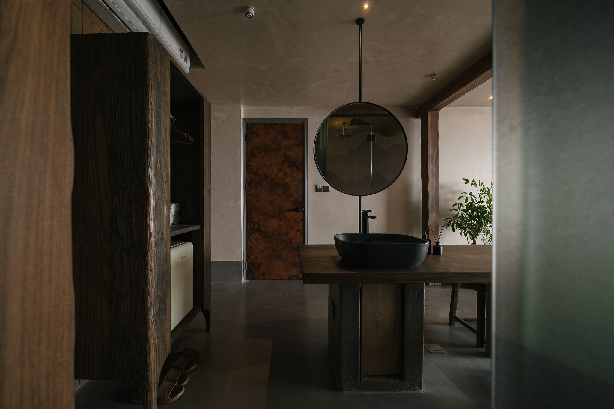A modern bathroom with a large mirror, a black basin, and a wooden vanity.