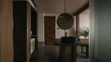 A modern bathroom with a large mirror, a black basin, and a wooden vanity.