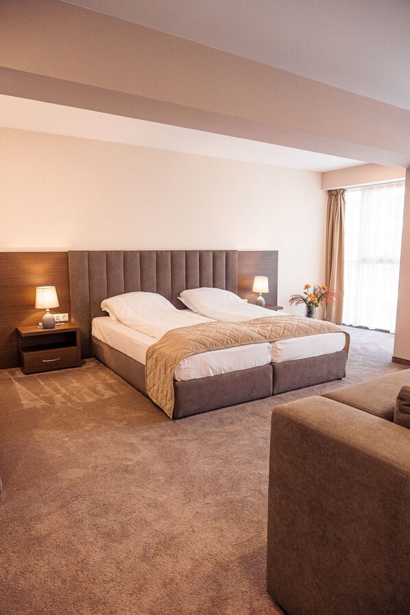 A hotel room with a large bed, two bedside tables with lamps, a sofa, and a window with curtains. - Luxuriöses Studio 6 by Interhome (Plovdiv)