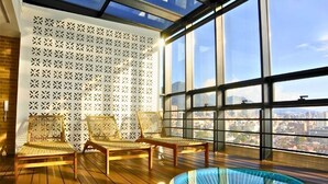 Una habitación soleada con ventanas amplias, piscina y sillas de mimbre.