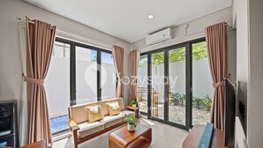 Ένα σύγχρονο σαλόνι με έναν καναπέ, ένα τραπεζάκι σαλονιού, μια τηλεόραση και κουρτίνες.