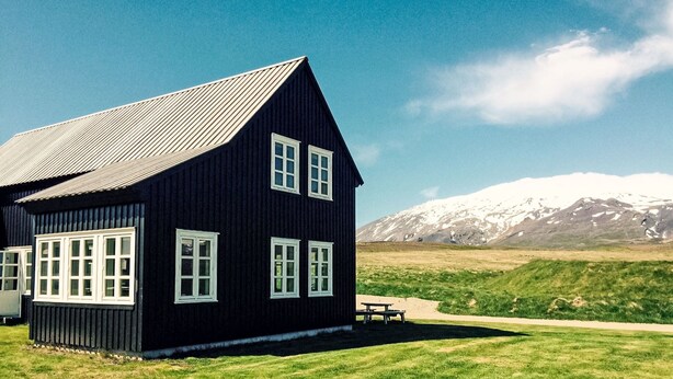 Et sort træhus med hvide detaljer, et skråt tag og flere vinduer.