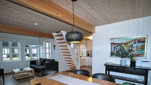 Et spiseområde med et træbord, sorte stole, en vævet spisebrik og en trappe til et højere plan.