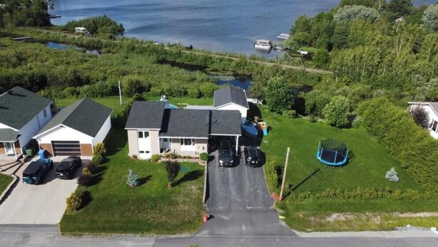 Un quartier résidentiel avec des maisons, une allée et un plan d’eau en arrière-plan.