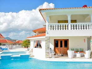 Ein zweistöckiges Haus mit Swimmingpool, Balkon und Bergblick.
