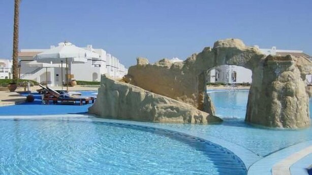 A swimming pool with a rock arch structure, a lounge area with a boat, and a building in the background. - Fewo Riviera Sharm by Interhome (Sharm El Sheikh)
