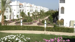 A row of white buildings with arched windows and a garden with white and pink flowers. - Fewo Riviera Sharm by Interhome (Sharm El Sheikh)
