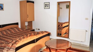 Ein Schlafzimmer mit Bett, Kleiderschrank, rundem Tisch und Spiegel.