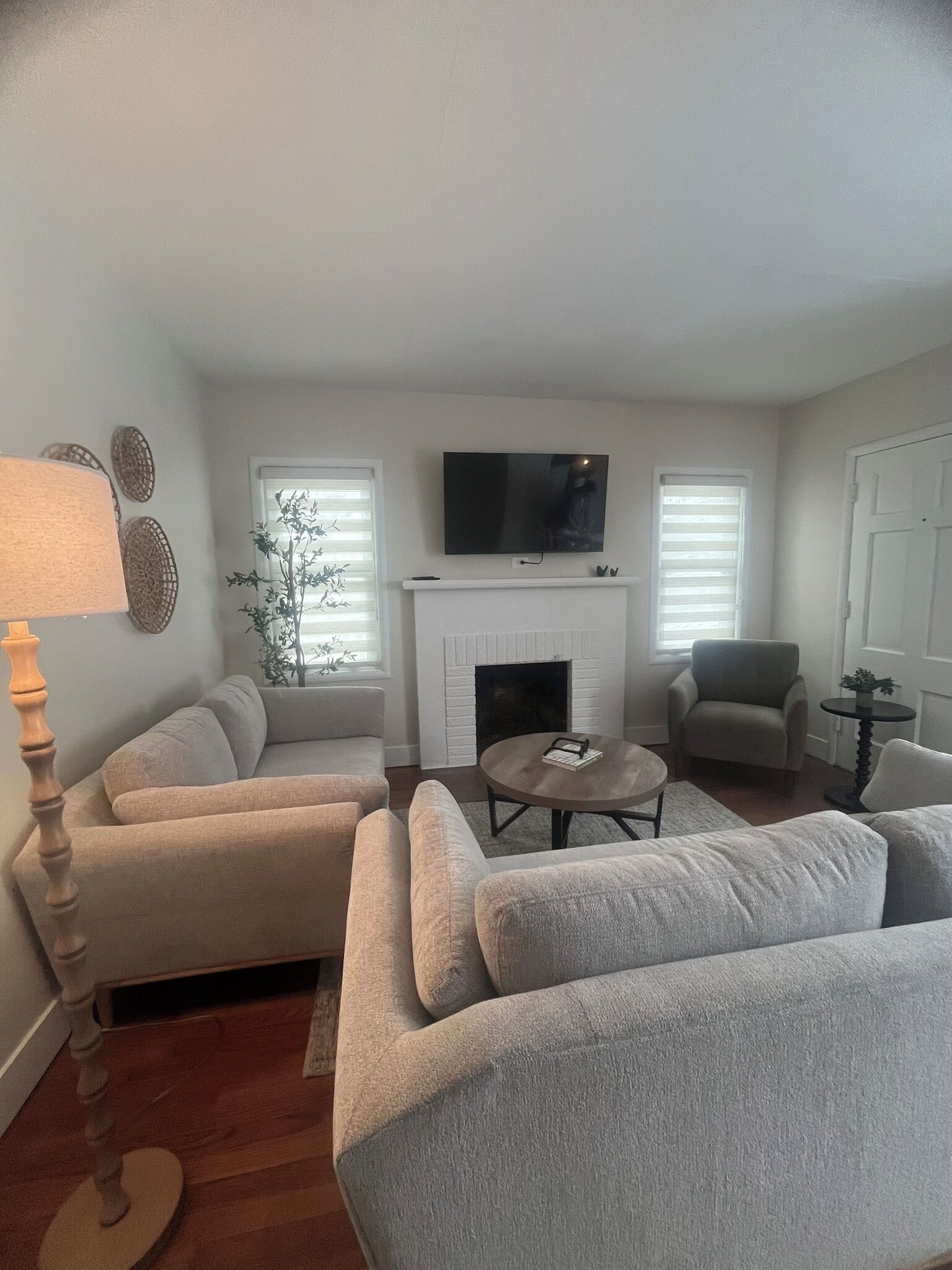 A living room with a fireplace, two sofas, a coffee table, and a TV mounted above the fireplace.