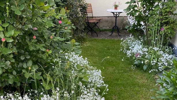 En have med hvide blomster, et bord og stole.