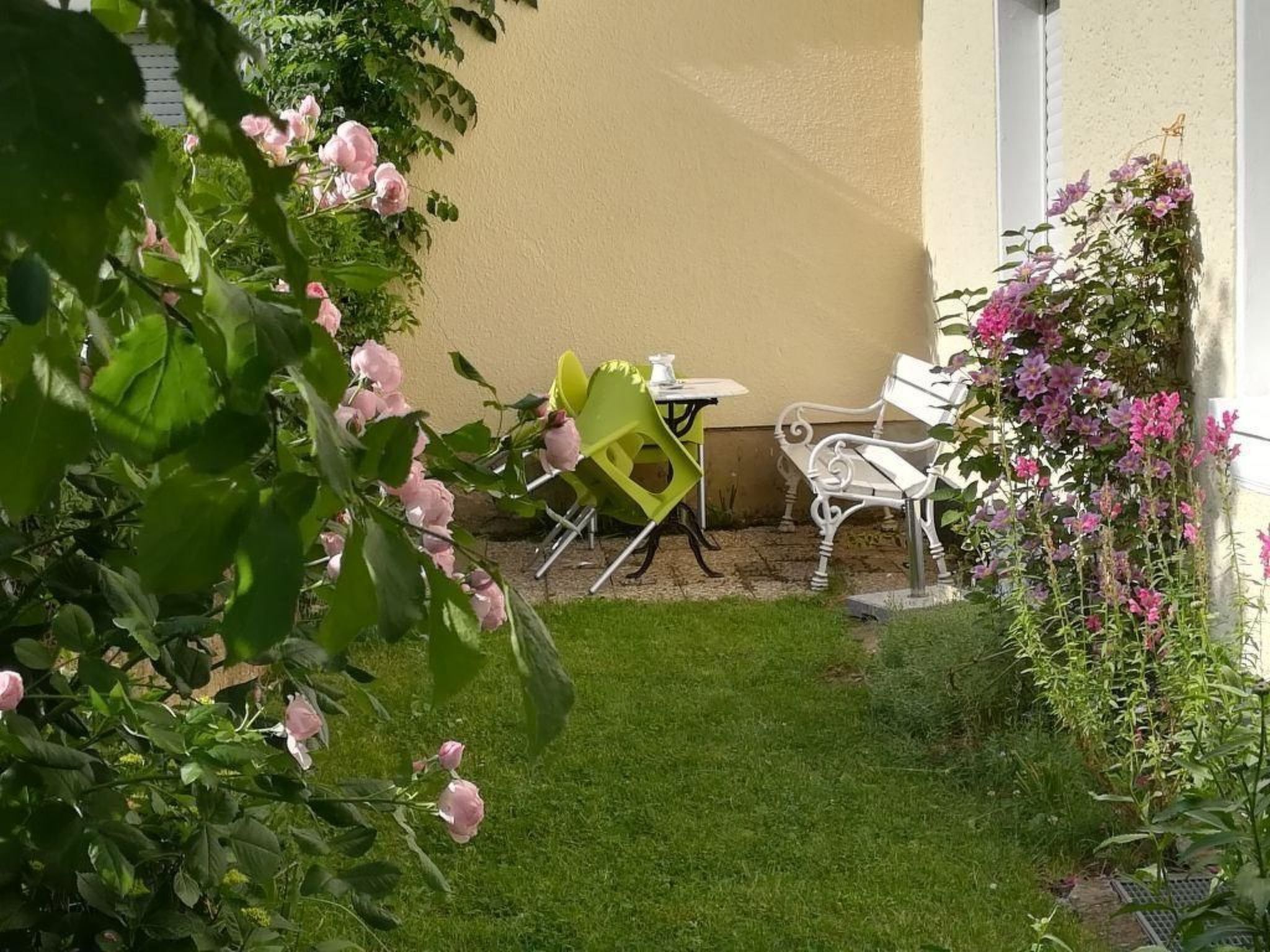 En liten uteplats med en vit stol, en gul stol och ett vitt bord.