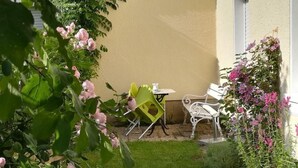 Eine kleine Terrasse mit einem weißen Stuhl, einem gelben Stuhl und einem weißen Tisch.