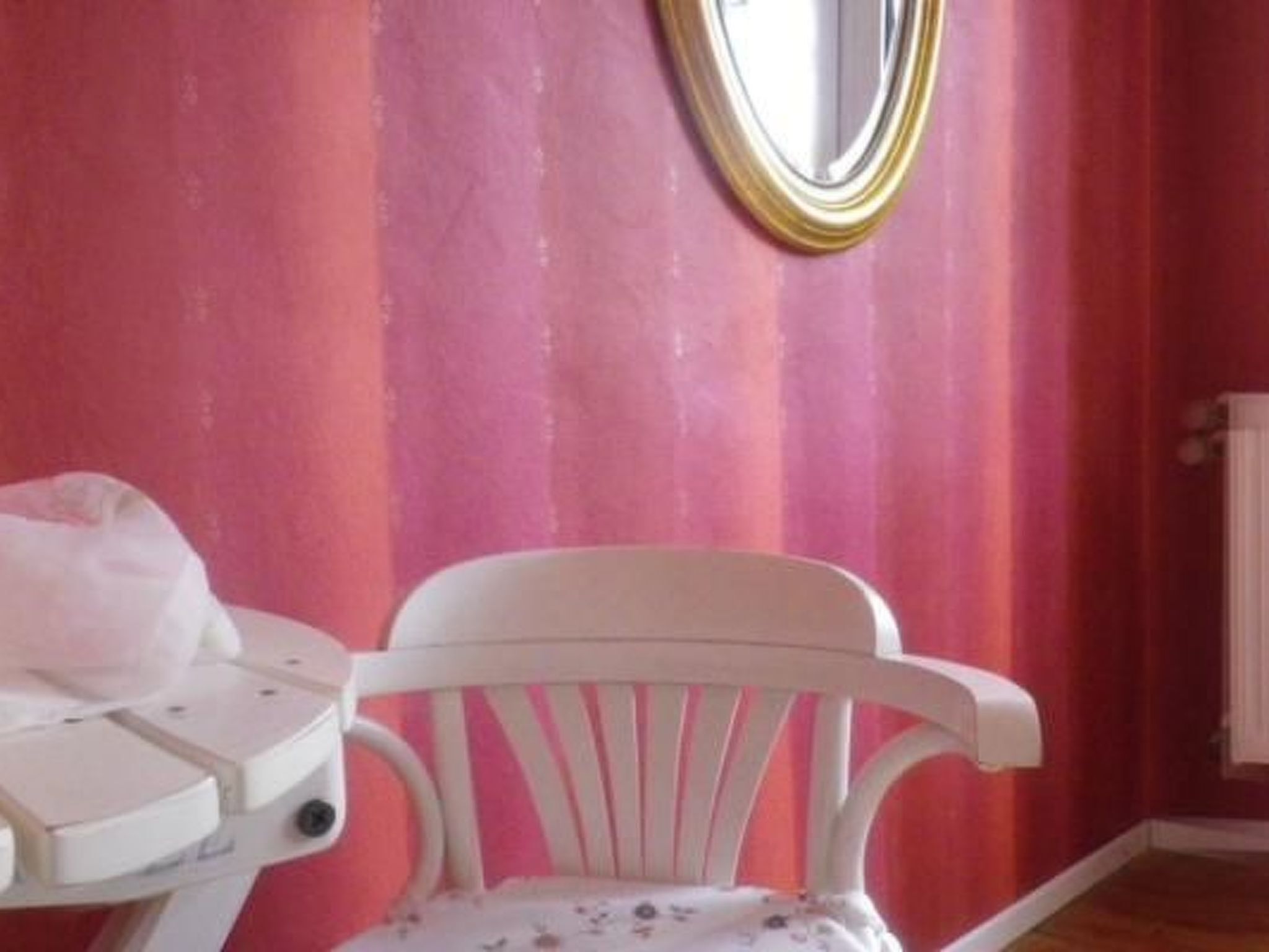 A room with a white chair, a small table, and a radiator.