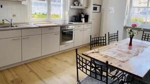 Eine moderne Küche mit weißen Schränken, einem Holztisch und einem schwarzen Metallstuhl.