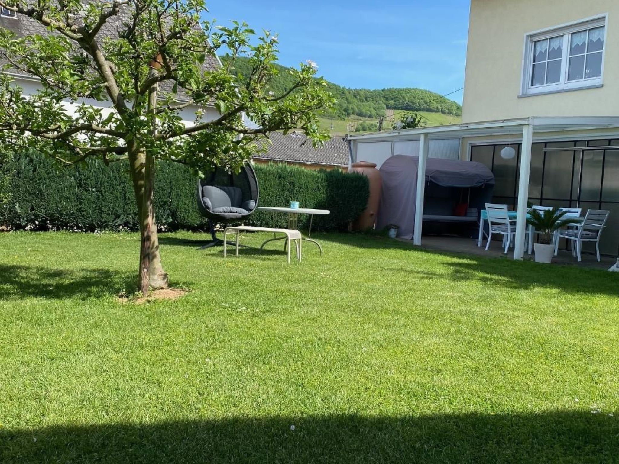 A well-maintained lawn with a patio area, outdoor seating, and a covered outdoor space.