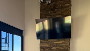 Una sala moderna con chimenea de piedra, un televisor de pantalla plana montado encima y un ventanal con vistas al exterior.