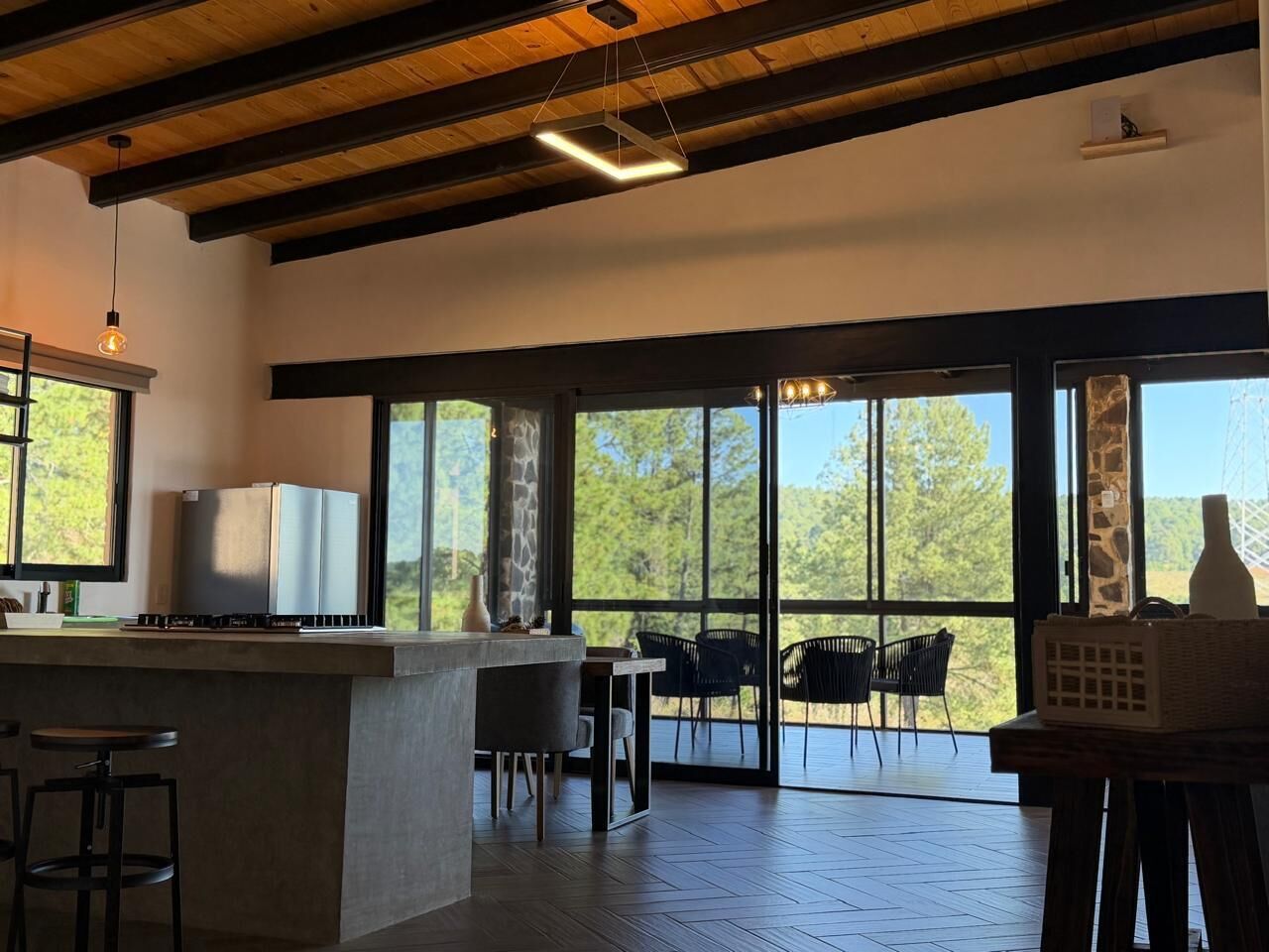 A modern kitchen with a bar area, large windows, and a view of the outdoors.