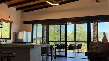 A modern kitchen with a bar area, large windows, and a view of the outdoors.