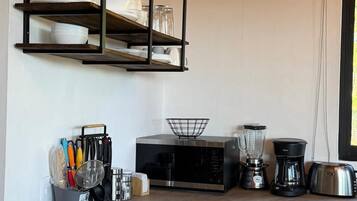 A kitchen with a microwave, blender, coffee maker, and utensils on the counter.