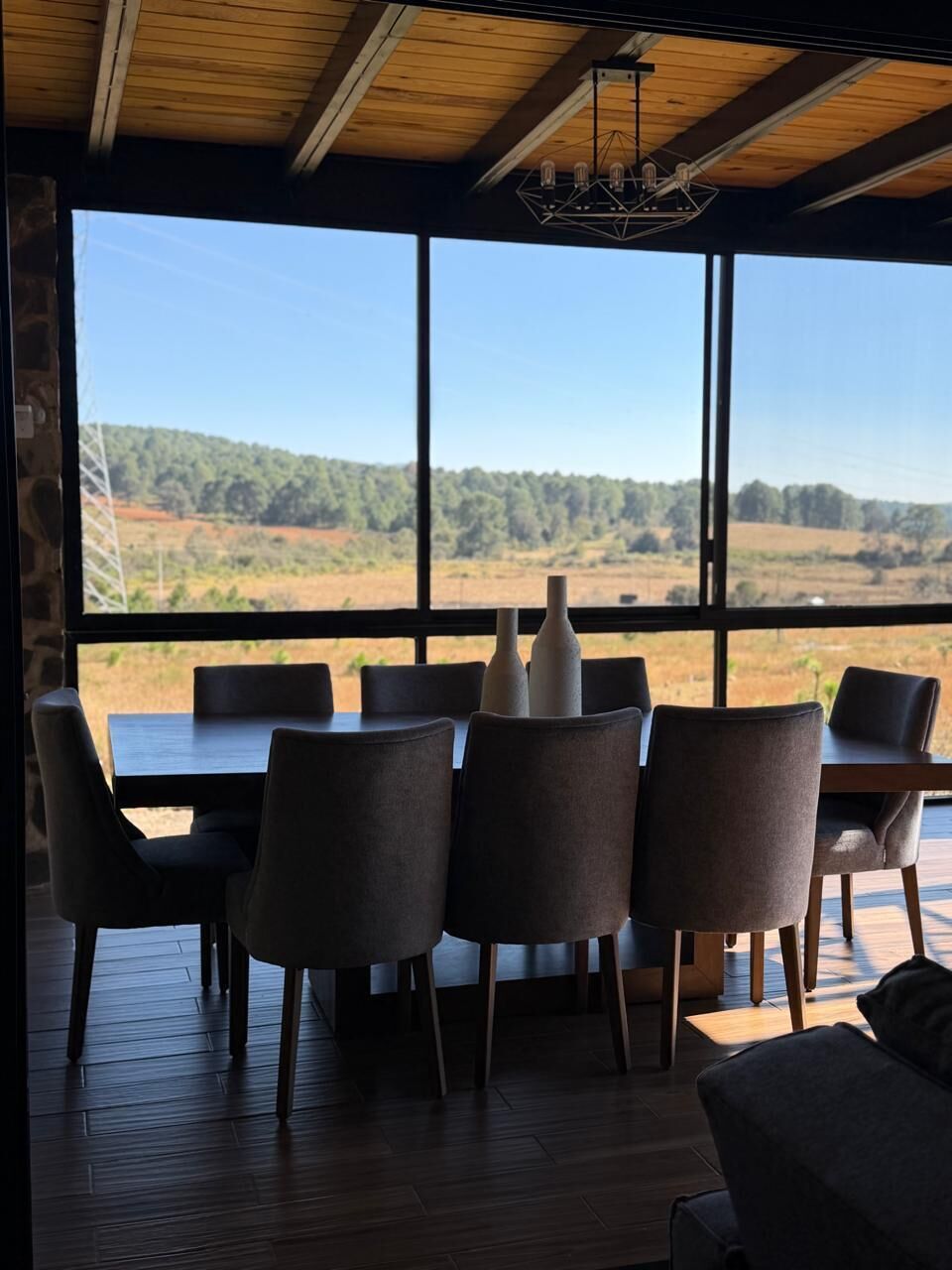 A dining area with a view of a landscape through large windows.