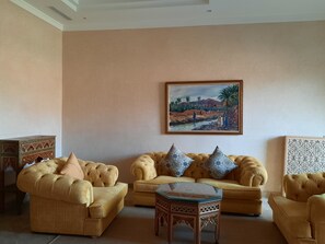 Un salón con un sofá color beige, cojines estampados, una mesita de centro de madera y un cuadro de un paisaje desértico en la pared.