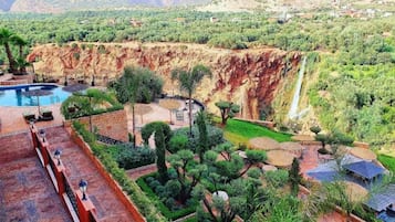 A resort with a swimming pool, outdoor seating, and a waterfall.