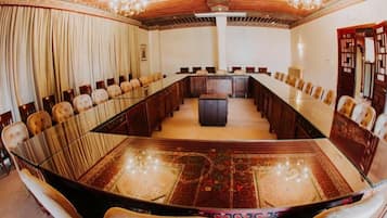 A conference room with a long table, chairs, and a central podium.