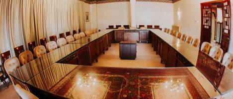 A conference room with a long table, chairs, and a central podium.