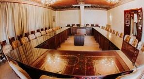 Une salle de conférence avec une longue table, des chaises et un pupitre central.
