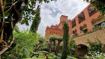 Un edificio amplio de estilo arquitectónico tradicional, rodeado de abundante vegetación y un puente de piedra.