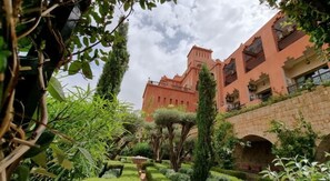 A large building with a traditional architectural style, surrounded by lush greenery and a stone bridge. - Borj Des Cascades & Spa (Ait Taguella)