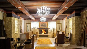 Un salon traditionnel avec une cheminée, un plafond décoré et des meubles classiques.