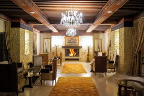 Un salon traditionnel avec une cheminée, un plafond décoré et des meubles classiques.