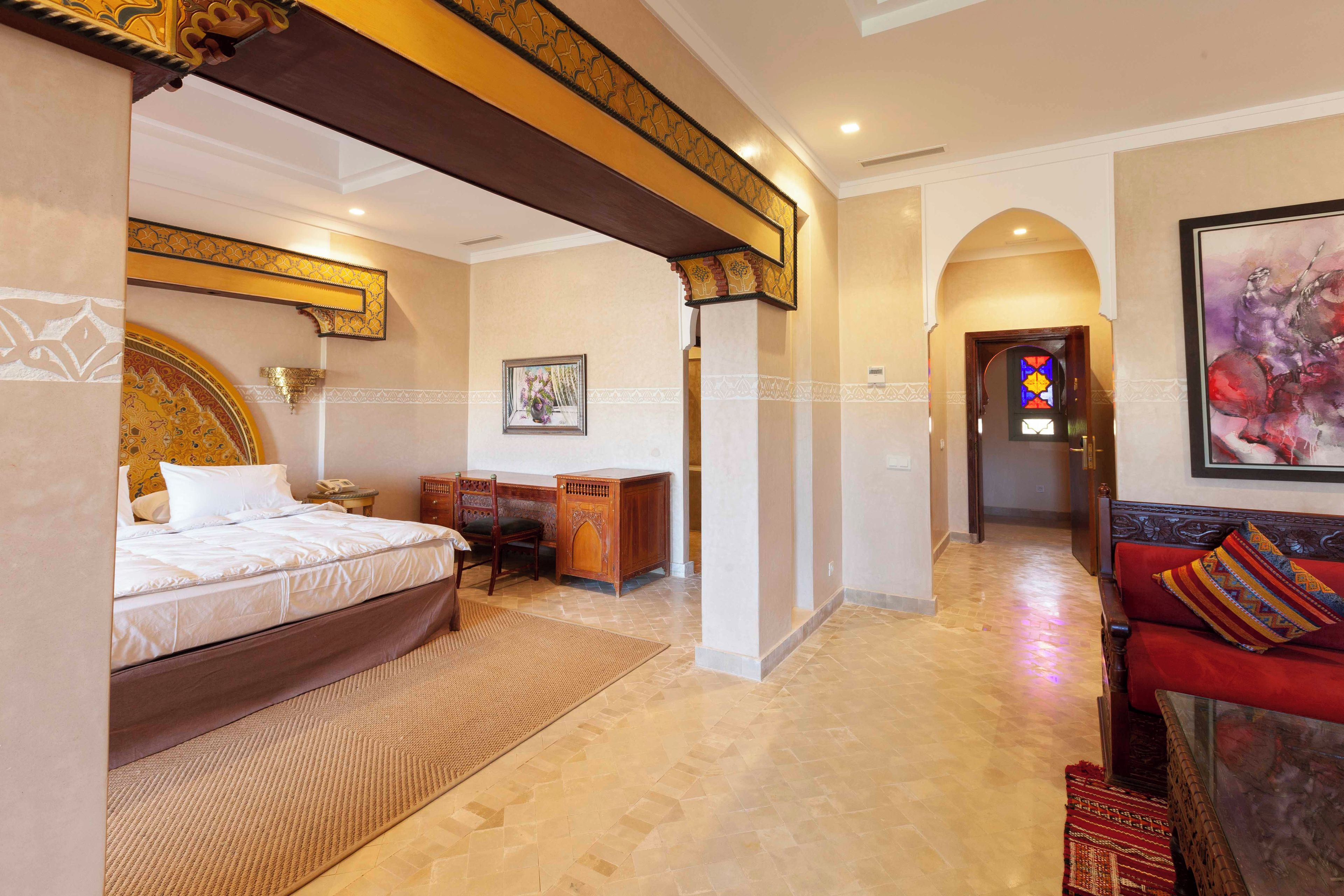 A hotel room with a bed, desk, and a red sofa.