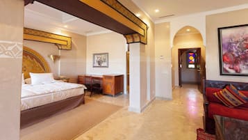 A hotel room with a bed, desk, and a red sofa.